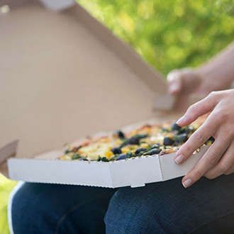 Zwei Hände halten Pizzaverpackung mit Pizza darin