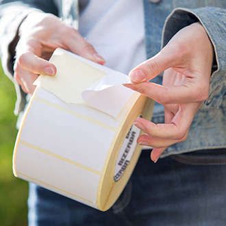 Zwei Hände halten eine Rolle Klebeetiketten